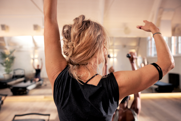 A woman in black gym clothes practising pilates seen from behind