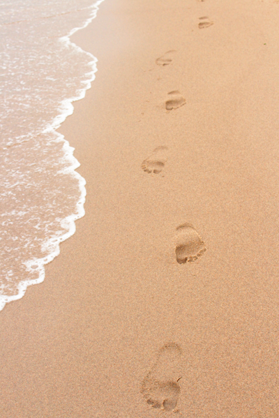Footprints in the sand next to the sea
