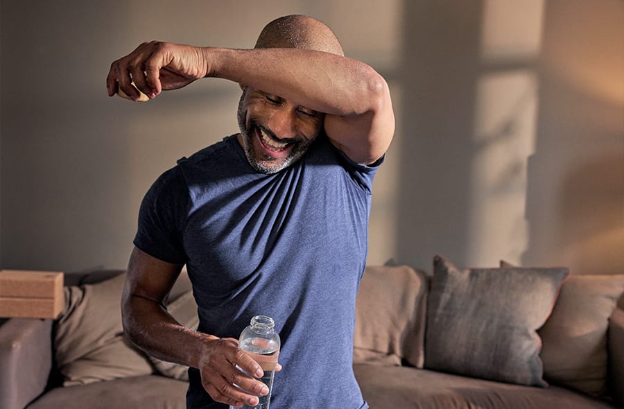 A man in his front room smiling and wiping his brow with joy