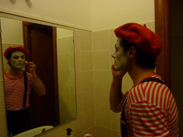 Clown putting on makeup in mirror