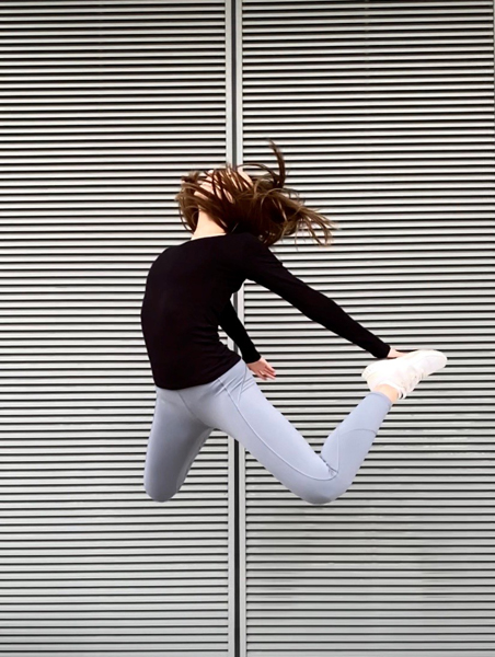 Woman jumping in front of grey wall