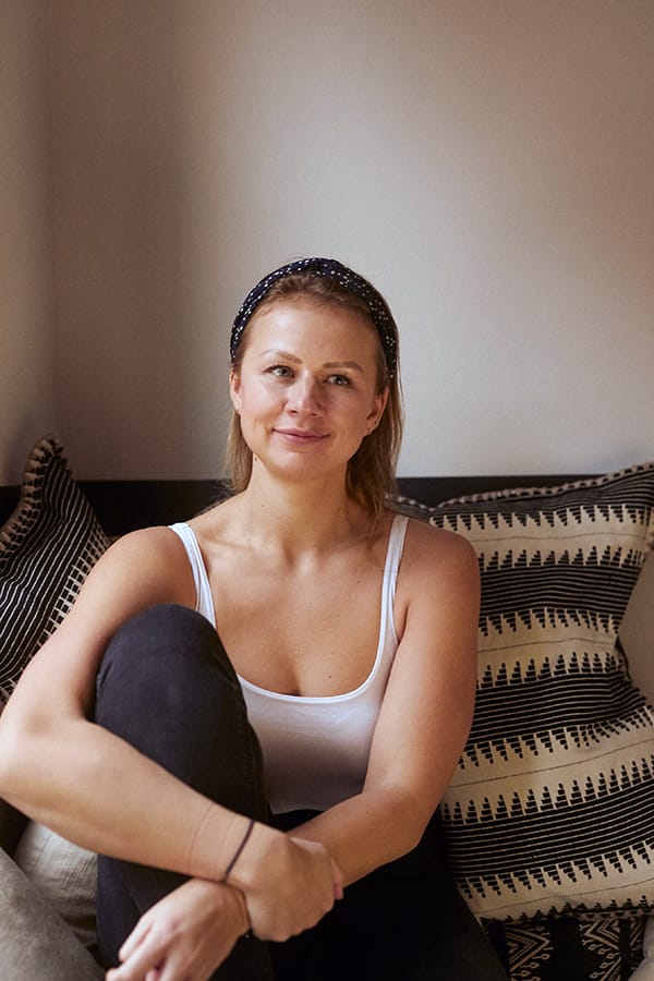 Uli Maslova smiling in a white tshirt on a sofa