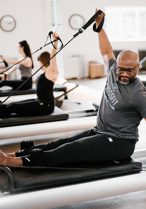 man sits on pilates machine and smiles